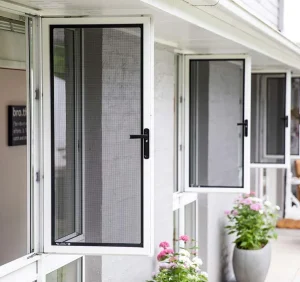 Open white-framed windows with insect screens and flower pots below.