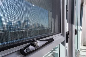 View of a city skyline through a mesh screen on a window.